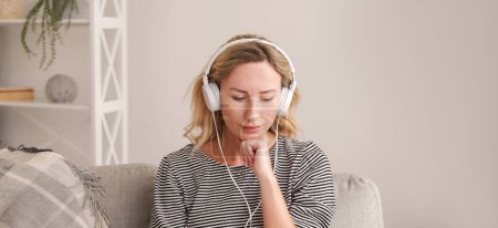 Photo for Music healing. Upset woman. Sound recovery. Depressed lady listening favorite melody on headphones sitting in light room interior. - Royalty Free Image
