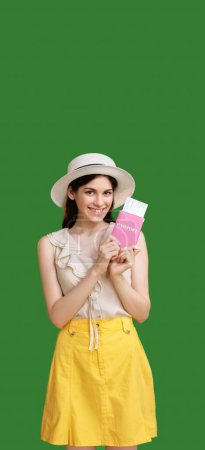 Téléchargez les photos : Voyage d'été. Bureau des visas. Jolie femme souriante en jupe jaune et chapeau tenant des billets de passeport à l'étranger vantant voyage isolé espace vert fond vide. - en image libre de droit