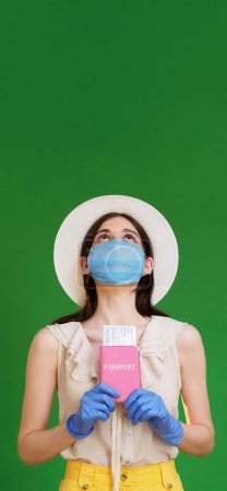 Photo for Covid-19 traveling. Passport control. Vacation trip. Attractive woman in medical mask gloves holding passport tickets looking up isolated green empty space background. - Royalty Free Image