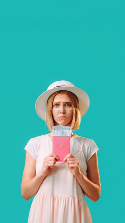Photo for Travel ban. Visa office. Holiday trip. Dissatisfied woman in white holding passport and tickets isolated on turquoise empty space background. - Royalty Free Image