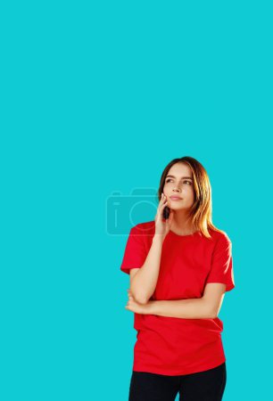 Photo for Think over plan. Puzzled woman. Uncertain situation. Beautiful girl in T-shirt holding chin dreaming looking away cunning expression isolated on cyan blue empty space background. - Royalty Free Image