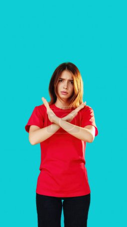 Photo for No way. Forbidden gesture. Stop sign. Serious displeased woman in red T-shirt crossed hands showing protest disapproval emotions isolated on cyan blue empty space background. - Royalty Free Image