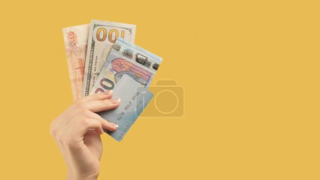 Photo for International transaction. Financial success. Woman with different types money credit card in hand on yellow background. - Royalty Free Image