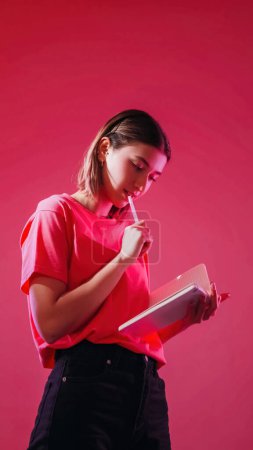 Photo for Think idea. Making checklist. Inspired student. Pensive girl writing paper notebook thoughtful expression to do list planning isolated on neon color pink background. - Royalty Free Image