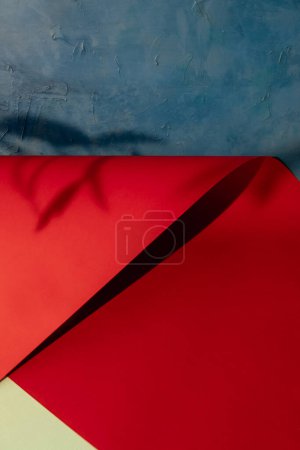 Photo for Paper display. Product presentation. Leaf foliage shadow on red blue blank folded sheet template abstract background with copy space. - Royalty Free Image