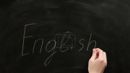 Photo for English school. Foreign language study. Female teacher hand writing word on black chalkboard. - Royalty Free Image