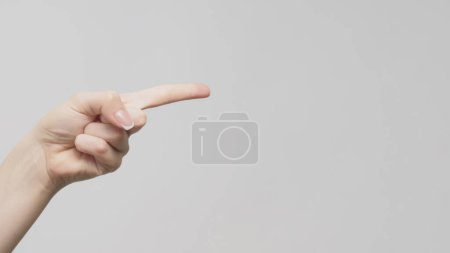 Foto de Señalando el gesto. Indicación manual. Mujer mostrando el dedo en el espacio de copia sobre fondo gris claro. - Imagen libre de derechos