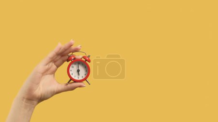 Photo for Time management. Progress achievement. Woman hand holding red alarm clock on yellow background copy space. - Royalty Free Image