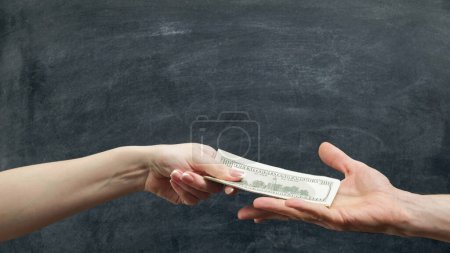 Photo for Money loan. Financial support. Man and woman hands holding dollars on chalkboard background. - Royalty Free Image