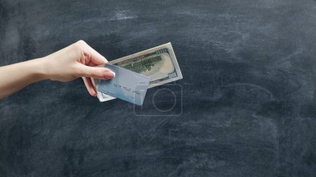 Photo for Money gestures. Bank account. Woman hand giving credit card and dollars cash on black chalkboard. - Royalty Free Image
