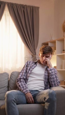 Photo for Depression anxiety. Negative emotion. Fatigue sadness. Young frustrated worried man sitting on sofa chin on hand at home in afternoon. - Royalty Free Image