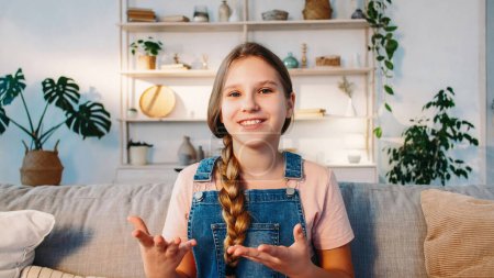 Photo for Influencer kid. Video presentation. Internet call. Confident smiling blogger girl talking gesticulating with hands on sofa in cozy room at home. - Royalty Free Image