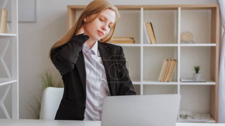 Téléchargez les photos : Fatigue informatique. Douleur au cou. Travail de bureau. Femme d'affaires épuisée en costume assis à la table avant le cou de frottement d'ordinateur portable avec les yeux fermés à l'intérieur léger. - en image libre de droit