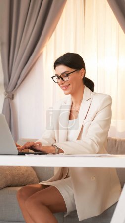 Photo for Office work. Laptop job. Confident executive business woman in suit doing professional tasks on computer sitting at workplace light interior. - Royalty Free Image