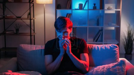 Photo for Malicious plan. Sarcastic man. Face expression. Nasty guy rubbing hands thinking about prank sitting sofa dark neon light home interior. - Royalty Free Image