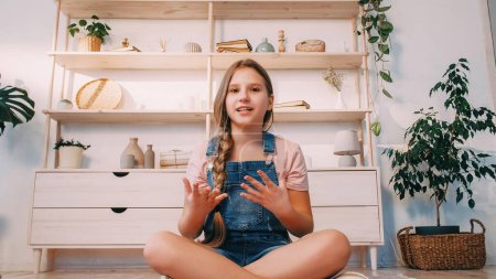 Photo for Childhood blog. Virtual event. Home vlogger. Inspired confident girl with motivational speech talking gesticulating sitting on floor crossed legs in light interior. - Royalty Free Image