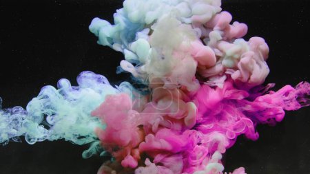 Foto de Una inyección de agua de tinta. Nube de humo. Explosión submarina. Pintura brillante de color azul rosado mezcla partículas de polvo salpicaduras de hojaldre sobre fondo abstracto negro oscuro del arte. - Imagen libre de derechos
