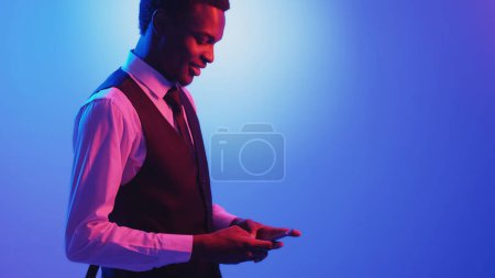 Photo for Business chat. Mobile app. Digital communication. Pink neon light smiling man texting message using phone on blue color empty space background. - Royalty Free Image