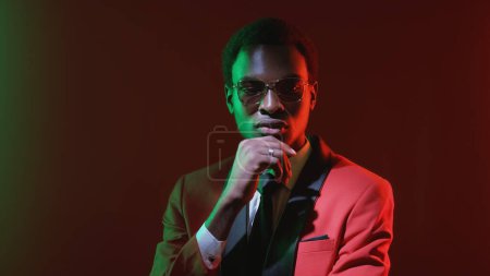 Photo for Pensive gentleman considering option. Green neon light confused perplexed business man in red tuxedo suit thinking on dark copy space background. - Royalty Free Image
