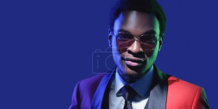 Photo for Masculine elegance. Eyewear fashion. Party accessories. Blue neon color light portrait of confident man face in glasses isolated on dark empty space background. - Royalty Free Image
