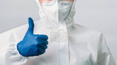 Photo for Lab scientist. Covid-19 protection. Like gesture. Unrecognizable healthcare doctor in white medical suit mask with hand thumb up sign isolated on grey background. - Royalty Free Image