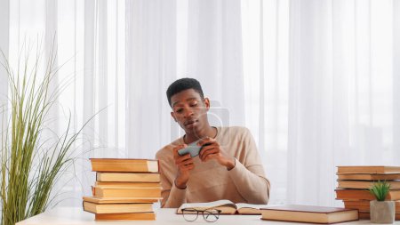 Photo for Gadget addiction. Phone distraction. Learning break. Irresponsible lazy young man student playing mobile game enjoying leisure at home in class interior. - Royalty Free Image