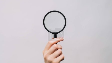 Photo for Magnifying loupe. Searching lens. Woman hand zooming empty space looking through glass exploring isolated on gray background. - Royalty Free Image