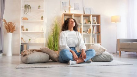 Photo for Home meditation. Yoga relax. Wellness leisure. Peaceful calm serene woman meditating in lotus pose on floor at cozy living room. - Royalty Free Image