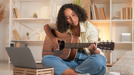 Foto de Practicando guitarra. Aprendizaje musical. Educación en línea. Mujer guitarrista tocando melodía estudiando instrumento de cuerda en clase de hogar portátil. - Imagen libre de derechos