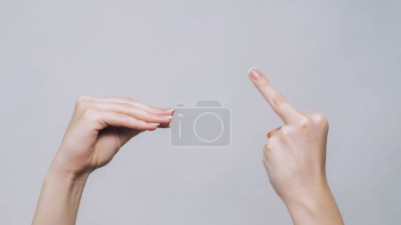 Foto de Blah gesture. Middle finger. Woman hands arguing showing fuck off quarrel demonstrating aggressive sign isolated on gray free space background. - Imagen libre de derechos