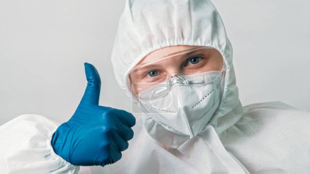 Photo for Healthcare scientist. Medical ppe. Thumb up gesture. Female woman doctor in virus infection protective equipment with approval like hand sign isolated on grey background. - Royalty Free Image