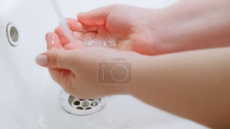 Photo for Clean hands. Bacteria prevention. Virus hygiene. Woman washing palms skin with water to protect from microbes infection spreading in white sink. - Royalty Free Image
