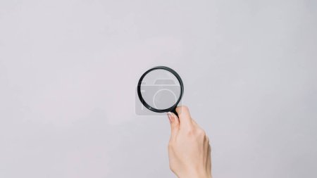 Photo for Zooming glass. Exploring lens. Woman hand studying empty space with magnifying loupe reading small text isolated on gray background. - Royalty Free Image