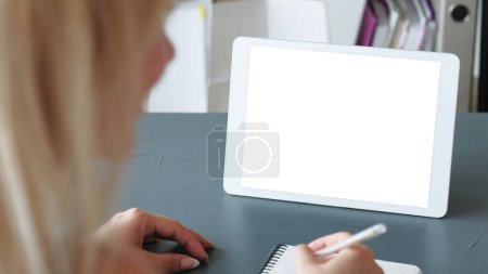 Foto de Aprendizaje online. Lección virtual. Mujer con bolígrafo en la mano en la tableta con espacio vacío mockup blanco de la pantalla de estudio en la clase de video internet en casa. - Imagen libre de derechos