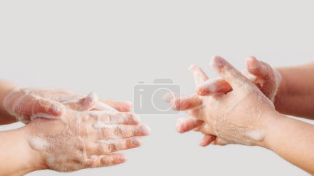 Téléchargez les photos : Nettoyage des mains. Hygiène infectieuse. Deux femmes lavent la peau des doigts de palme avec de la mousse de savon désinfectante antibactérienne isolée sur fond blanc. - en image libre de droit