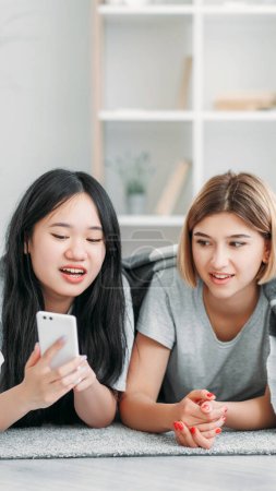 Photo for Gadget leisure. Technology fun. Content consumption. Two young teenagers girls scrolling social media blog on mobile device at cozy interior at home. - Royalty Free Image