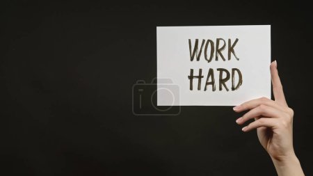Photo for Work hard. Life challenge. Success motivation. Female hand holding supporting word sign banner on dark black empty space background. - Royalty Free Image