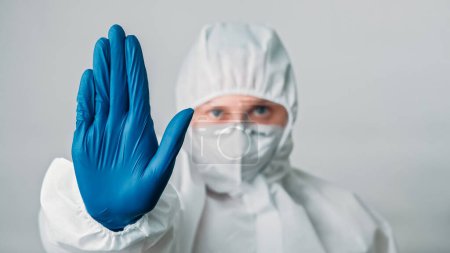 Photo for Stop disease. Infection protection. Virologist doctor. Female woman medical healthcare specialist in white ppe suit warning hand gesture in blue gloves isolated on grey background. - Royalty Free Image