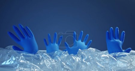 Photo for Stop pollution. Climate change. Marine contamination. Blown medical gloves floating in abstract sea water from used wet bottles isolated on blue background empty space. - Royalty Free Image
