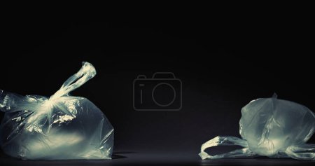 Foto de Contaminación plástica Gestión de residuos. Detener la contaminación. Usado bolsas desechables de celofán soplado basura aislada en el espacio vacío de fondo oscuro. - Imagen libre de derechos