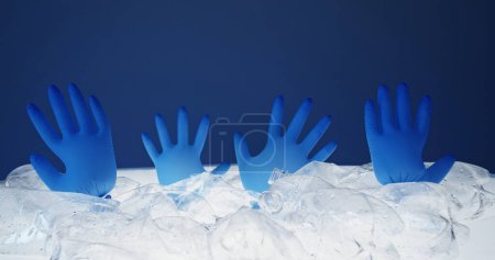 Photo for Marine pollution. Earth contamination. Blown medical gloves drowning in abstract ice water from crushed wet plastic bottles pile isolated on blue background empty space. - Royalty Free Image