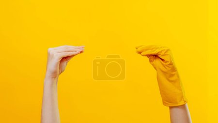 Photo for Household product advertising. Cleaning play. Socks show imitation. Woman hand meeting arm in protective gloves talking quarreling isolated on yellow background copy space. - Royalty Free Image
