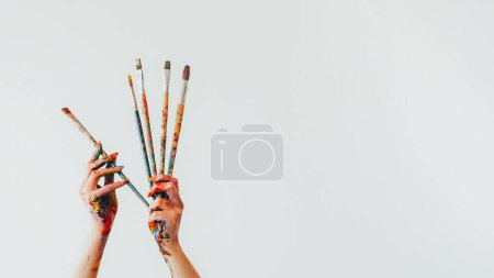 Photo for Art accessories. Painting tools. Woman artist hand holding messy gouache paint colorful paintbrush artistic equipment isolated on white copy space background. - Royalty Free Image