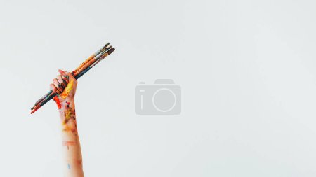 Photo for Painting brush. Art accessories. Unrecognizable woman painter hand holding messy acrylic paint colorful kit of paintbrushes isolated on white empty space background. - Royalty Free Image