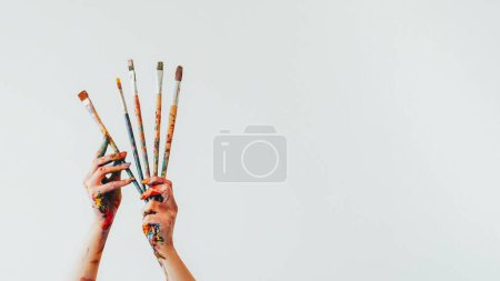 Téléchargez les photos : Fournitures de peinture. Des outils artistiques. Femme peintre main avec ensemble de kit coloré salissant de pinceaux équipement artiste isolé sur fond d'espace de copie blanche. - en image libre de droit