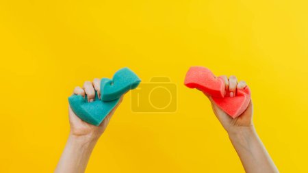 Photo for House chores. Domestic cleaning. Janitor services. Woman hands squeezing green pink washing sponges on isolated on yellow background copy space. - Royalty Free Image