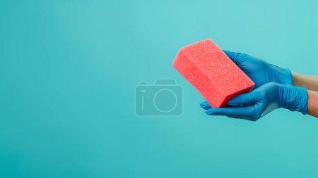 Photo for Dirty surface. Home wiping. Hygiene cleaning. Pink dust removing sponge in janitor hands in blue latex gloves isolated on green background empty space. - Royalty Free Image