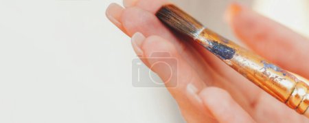 Photo for Artist paintbrush. Drawing equipment. Closeup of woman hand with worn dirty brush in acrylic paint isolated on light background free space. - Royalty Free Image
