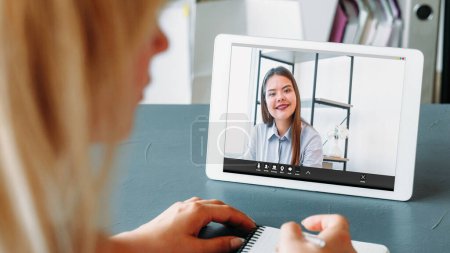 Photo for Video briefing. Remote conference. Cheerful woman employee discussing project with female business colleague on tablet screen at modern home office workplace. - Royalty Free Image