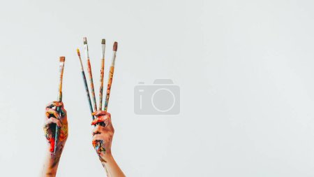 Téléchargez les photos : Matériel d'artiste. Un pinceau. Femme peintre mains tenant ensemble de pinceaux colorés désordonnés isolés sur fond blanc vide. - en image libre de droit